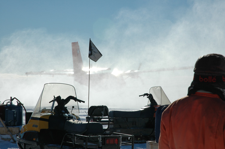 Twin Otter kicks up snow as she flies off