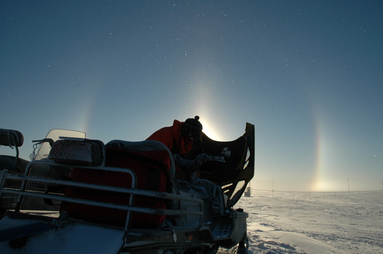 Vicki clears snow from a skidoo beneath a halo